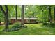 Quaint brick ranch-style home nestled among mature trees with lush landscaping and inviting curb appeal at 7021 Linda Lake Dr, Charlotte, NC 28215