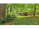 Single-story brick home with mature trees and manicured lawn providing a serene setting at 7021 Linda Lake Dr, Charlotte, NC 28215
