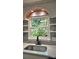 Close-up of the kitchen sink featuring a garden window overlooking the lush greenery outside at 7021 Linda Lake Dr, Charlotte, NC 28215
