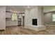 Open living room features white brick fireplace, wood look flooring, and a view into the kitchen at 7021 Linda Lake Dr, Charlotte, NC 28215