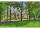 Brick home with mature trees. View of the home through the trees on the front lawn at 706 Evans Manor Dr, Weddington, NC 28104