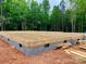 Image shows a new home foundation with gray cinder blocks and wooden construction with a wooded area in the background at 762 Highway 274 Rd, Clover, SC 29710