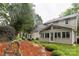 A cozy backyard featuring a stone patio, lush greenery, and an attached sunroom with large windows at 8532 Piccone Brook Ln, Charlotte, NC 28216