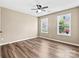 Bedroom features wood-look floors, a ceiling fan, and ample natural light from two windows at 8610 Sawleaf Ct, Charlotte, NC 28215