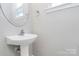 Bathroom featuring pedestal sink with modern faucet and round mirror at 10606 Gallowgate Ln, Charlotte, NC 28213