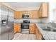 Well-lit kitchen featuring stainless steel appliances, granite countertops, and wood cabinets at 10606 Gallowgate Ln, Charlotte, NC 28213