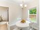 Cozy dining room with a white round table, four chairs, modern chandelier, and natural light from the window at 107 S Sina St, Troutman, NC 28166