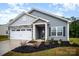 Charming gray home featuring a two-car garage, stone accents, manicured lawn and covered front porch entrance at 107 S Sina St, Troutman, NC 28166