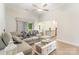 Bright living room featuring a comfortable gray sectional sofa, coffee table, ceiling fan, and natural light at 107 S Sina St, Troutman, NC 28166