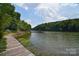 Scenic lake view with lush trees along the shoreline and a wooden walkway, creating a serene waterfront setting at 108 Britt Ln, New London, NC 28127
