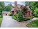 Charming brick Tudor-style home with a red door, lush landscaping, and a detached garage at 1136 S Edgemont Ave, Gastonia, NC 28054