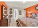 Nicely decorated bedroom with orange accent wall and dresser with mirror to adjacent bathroom at 12217 Dearview Ln, Charlotte, NC 28269