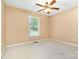 Neutral bedroom features a ceiling fan and bright window looking out to the front yard, with plush carpet at 1318 Candlewood Dr, Gastonia, NC 28052
