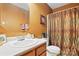 Well-lit bathroom featuring a single sink vanity, toilet, and shower with a tan patterned shower curtain at 1332 Waterlily Ln, Charlotte, NC 28262