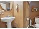 Stylish powder room featuring a pedestal sink, decorative mirror, and elegant earth-toned walls at 1332 Waterlily Ln, Charlotte, NC 28262