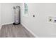 Bright laundry room with gray wood-look floors, water heater, and utility connections at 1408 Delview Rd, Cherryville, NC 28021