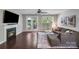 Cozy living room with fireplace, fan, hardwood flooring, and a large window at 14512 Brotherly Ln, Charlotte, NC 28278