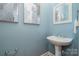 Powder room with blue walls featuring a pedestal sink, a decorative mirror and abstract paintings at 14822 Rocky Top Dr, Huntersville, NC 28078