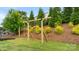 Grassy backyard with a wooden swing set on the hill and mature landscaping at 1620 Callahan Rd, Fort Mill, SC 29715