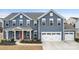 Charming two-story home showcasing a blue exterior, red door, manicured landscaping, and an attached two-car garage at 1620 Callahan Rd, Fort Mill, SC 29715