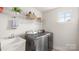 Well-lit laundry room with a large sink, stainless steel washer and dryer, and wire shelving at 1620 Callahan Rd, Fort Mill, SC 29715