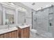 Modern bathroom featuring double sinks, wood cabinets, a toilet, and a glass-enclosed shower with marble tile at 1829 Jennings St, Charlotte, NC 28216