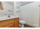 Clean bathroom with wooden vanity, white sink, shelving, and shower featuring a curtain at 197 Devon Forest Dr, Mooresville, NC 28115
