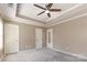 Bedroom with tray ceiling, ceiling fan, and multiple closets for storage at 197 Devon Forest Dr, Mooresville, NC 28115
