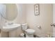 Clean powder room featuring a pedestal sink, toilet, decorative mirror, and neutral wall color at 2014 Drawbridge Dr, Fort Mill, SC 29707