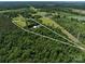 Wide aerial view of the property, featuring a large barn, pond, and acres of beautiful surrounding woodlands at 2500 Cedar Cove Dr, Harrisburg, NC 28075