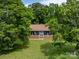 Charming exterior view of the home with a welcoming porch, set amongst mature trees and green lawn at 2500 Cedar Cove Dr, Harrisburg, NC 28075