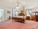 Spacious bedroom featuring a four-poster bed, pink carpet, and neutral walls at 2500 Cedar Cove Dr, Harrisburg, NC 28075