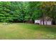 Backyard with a shed, lounging chairs, a fire pit, and mature trees for shade and privacy at 328 Whippoorwill Rd, Mooresville, NC 28117