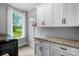 Bright laundry room featuring granite countertops, storage cabinets, and a window overlooking a lush green landscape at 3707 Seagrave Farm Rd, Concord, NC 28025