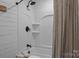 Bathroom featuring a bathtub with shower, vertical white shiplap, and modern fixtures at 5229 Mt Holly Huntersville Rd, Charlotte, NC 28216