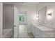 Bathroom with a tub, white vanity, gray tile, and a view into another bedroom with ceiling fan at 536 Hillside Ave, Charlotte, NC 28209