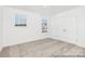 A light-filled bedroom featuring neutral carpet, two windows, and a double door closet at 5630 Galloway Dr # 49, Stanfield, NC 28163