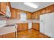 Kitchen featuring wooden cabinets, white appliances, laminate countertops, and hardwood floors at 5678 Cedar Run Dr, Denver, NC 28037