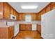 Kitchen featuring wooden cabinets, white appliances, laminate countertops, and hardwood floors at 5678 Cedar Run Dr, Denver, NC 28037