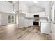 Open-concept kitchen featuring stainless steel appliances, white cabinets, and wood floors at 6022 Windsong Way, Wingate, NC 28174