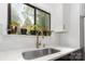 Close-up on kitchen sink shows a white countertop, gold faucet, and plants on the window sill at 6824 Cortez Trl, Charlotte, NC 28227