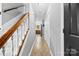 Hallway leading to the kitchen featuring tile floors and a staircase with white railings and wooden banister at 7321 Mapleridge Dr, Charlotte, NC 28210