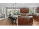 Open-concept kitchen featuring a central island with barstool seating, wooden cabinets, and view of a dining area at 7501 Cleyera Cir, Waxhaw, NC 28173