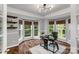 Home office featuring hardwood floors, a modern desk, decorative shelving, and bay windows with natural light at 7501 Cleyera Cir, Waxhaw, NC 28173