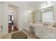 Bright bathroom featuring double sinks, white cabinetry, and a large mirror reflecting natural light at 7507 Meadowgate Ln, Waxhaw, NC 28173