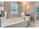 Bright bathroom features a large soaking tub with tile surround and vanity with sink at 8726 Addingham Dr, Charlotte, NC 28269