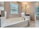 Bathroom has large white tub, neutral tile, and window for natural light at 8726 Addingham Dr, Charlotte, NC 28269