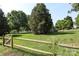 Well-maintained front yard with lush lawn, mature trees, and a charming wooden fence at 9315 Pebble Creek Way, Charlotte, NC 28269