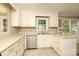 Well-lit kitchen featuring stainless steel dishwasher, sink, and white cabinets at 9315 Pebble Creek Way, Charlotte, NC 28269