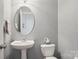 Cozy half bathroom with pedestal sink, oval mirror, and neutral color scheme at 10401 Royal Winchester Dr, Charlotte, NC 28277